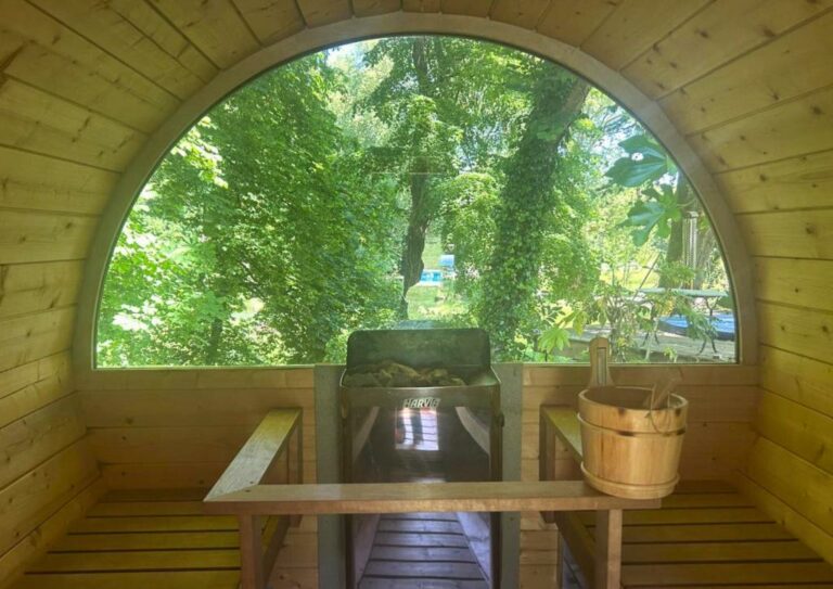 Intérieur du sauna tonneau, avec sa baie vitrée ouverte sur le parc